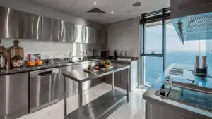 Roasting meat with the sea as a backdrop. Chef's kitchen in a penthouse flipping kitchen